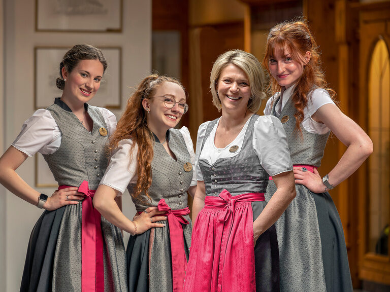 Eine Gruppe glücklicher Rezeption Mitarbeiter steht im Empfangsbereich des Wellness & SPA Resort Mooshof im Bayerischen Wald.